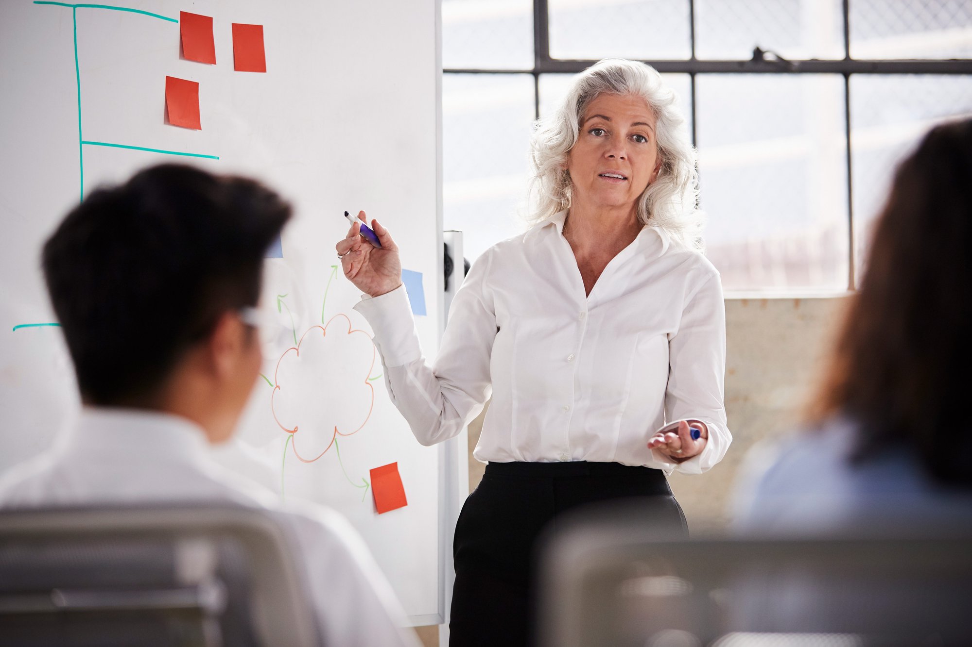 senior-businesswoman-using-whiteboard-meeting-close-up